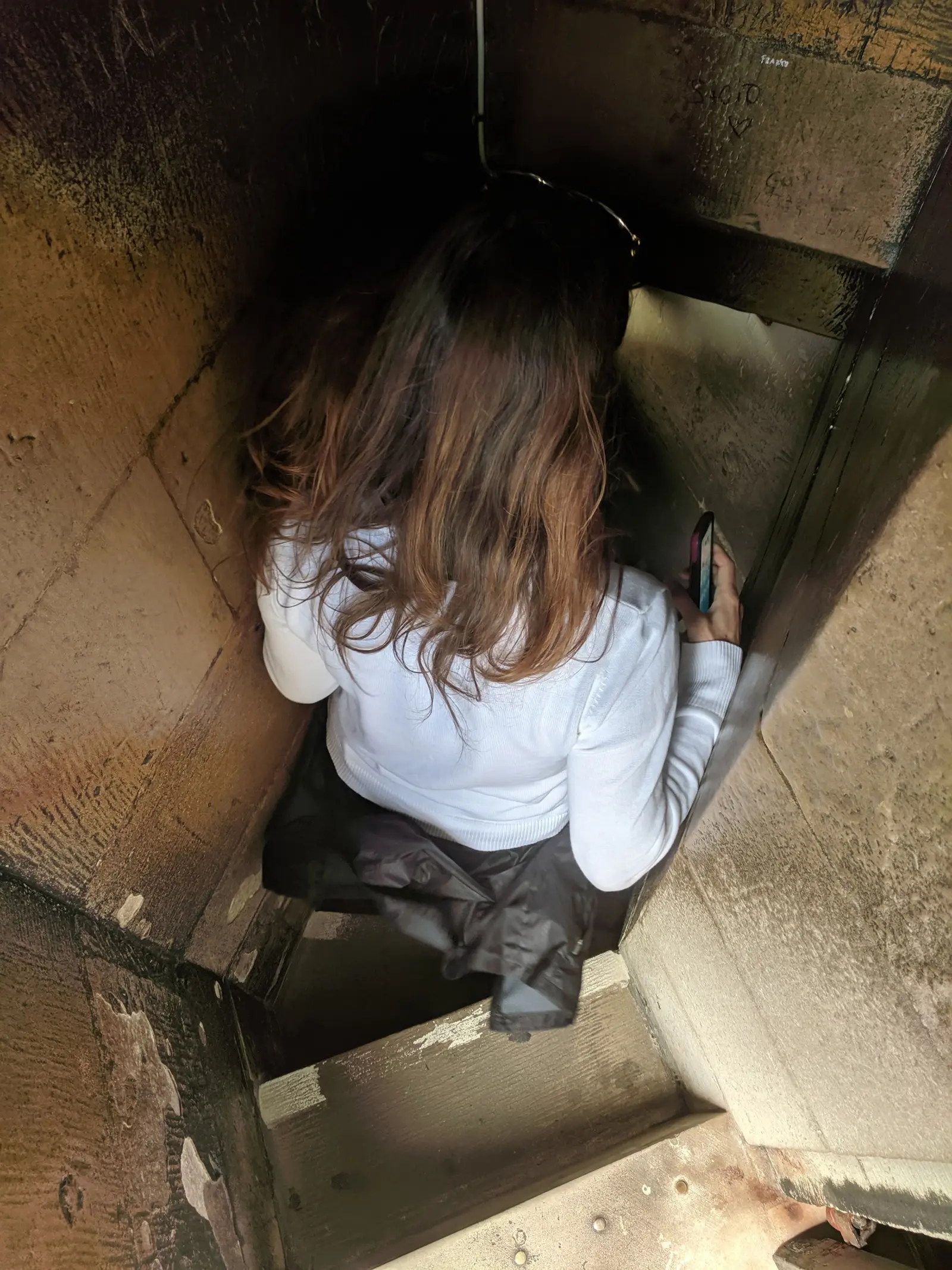 A visitor descending a cramped stone spiral staircase between the inner and outer shells of St Paul's dome