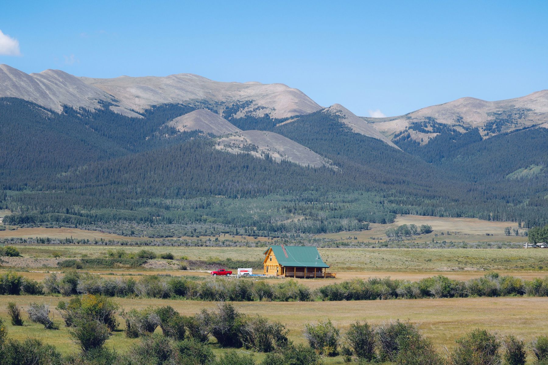 A solitary cabin with mountains in the background, a serene natural setting.